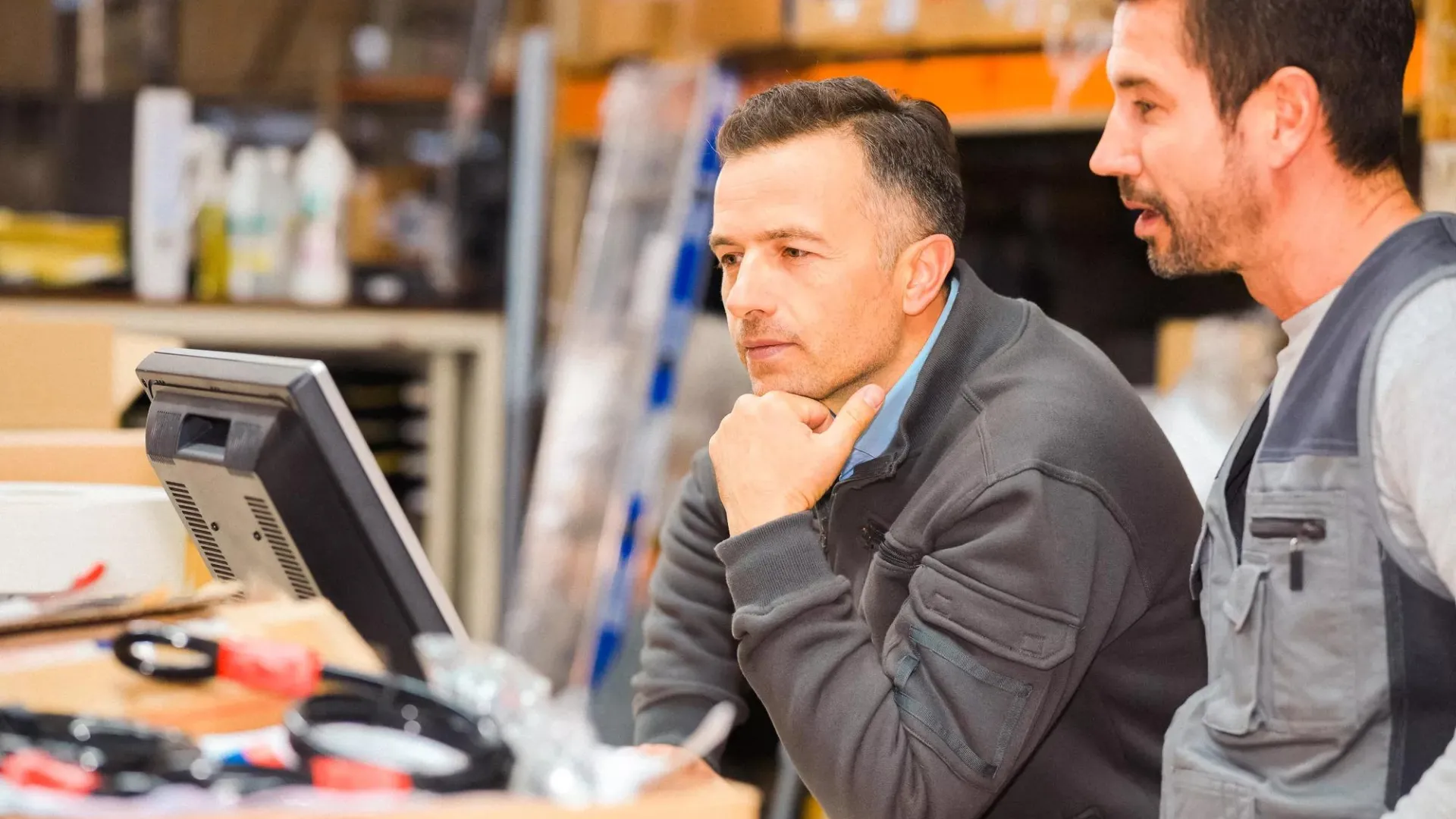 Two employees looking at a computer screen together in a work setting.